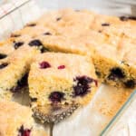 geschnittene Stücke Blaubeerkuchen in Glasbackform, ein Stück auf Tortenheber