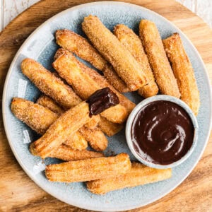 Airfryer Churros auf blauem Teller mit Schokoladensauce, einer wurde reingetaucht, von oben