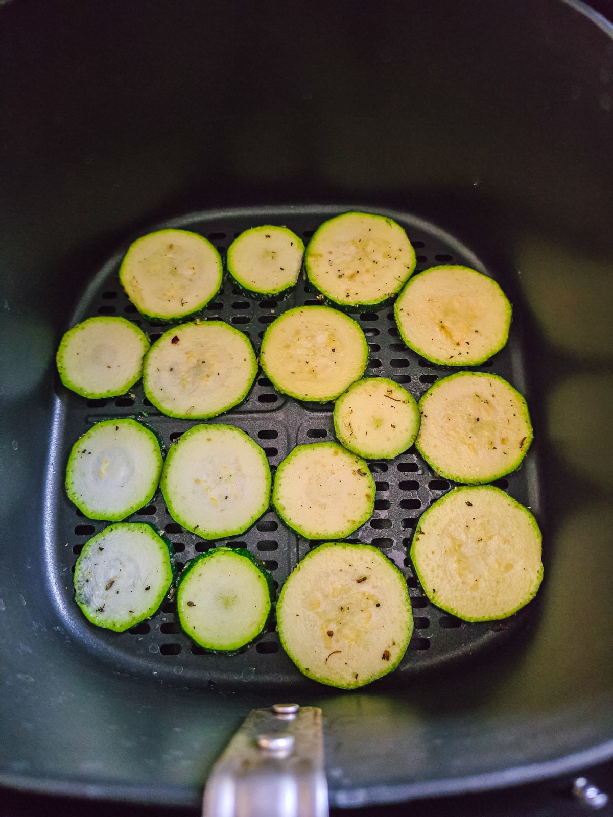 Rohe Zucchinischeiben in einer Lage im Korb des Airfryers