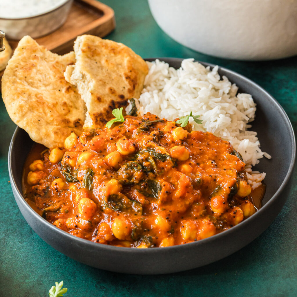 Kichererbsencurry mit Reis und Naan in dunkelgrauer Schale