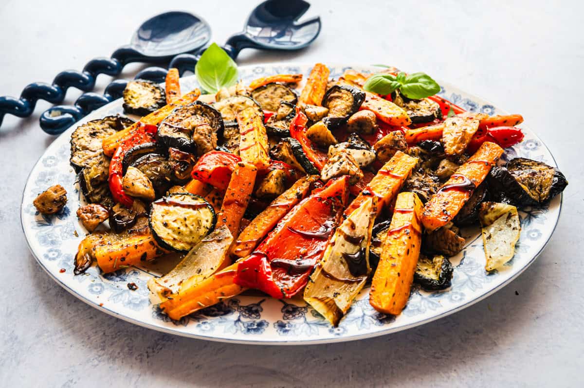 Gemischte Antipasti auf einer weißen Platte mit blauem Blumenmuster am Rand,
