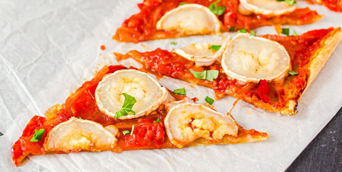 Blätterteigtarte mit Tomaten und Ziegenkäse auf weißem Papier