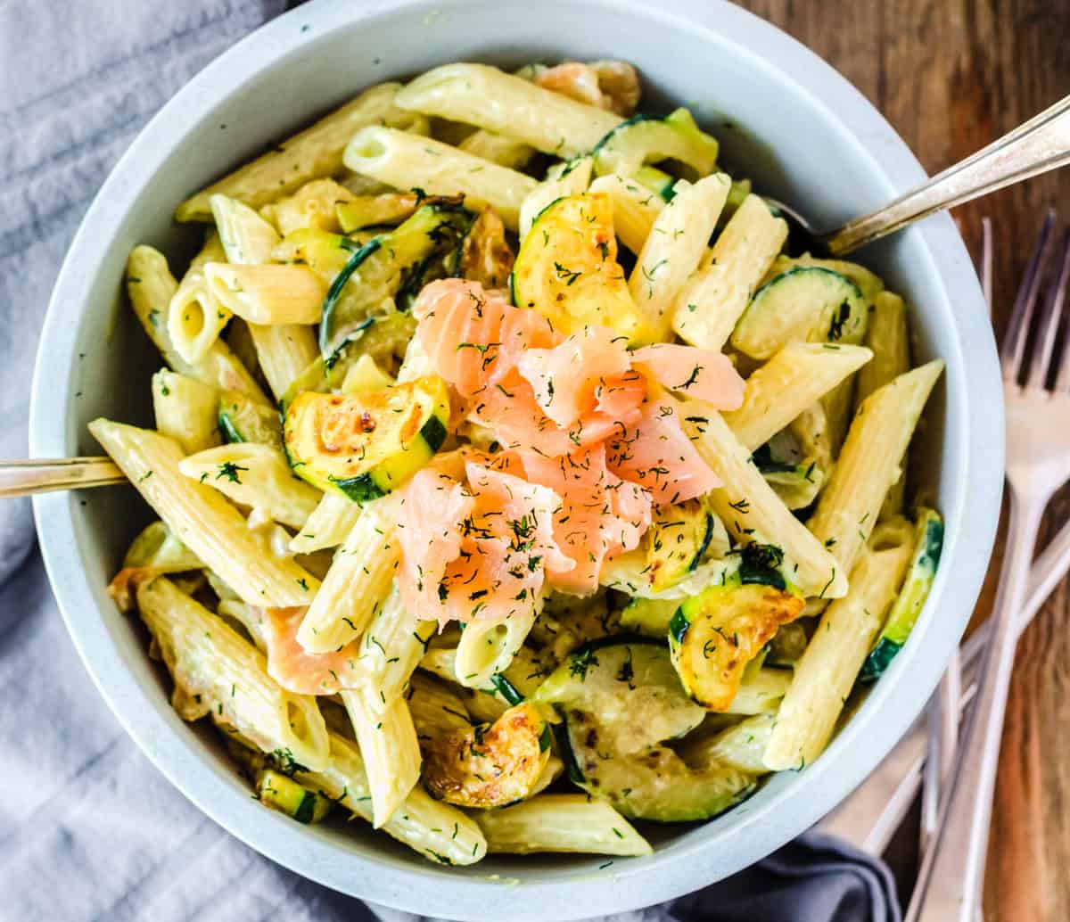 Nudelsalat mit Lachs und Zucchini in hellblauer Schale von oben